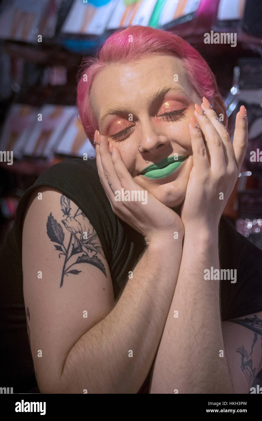 Porträt einer jungen Frau von Transgender mit rosa Haaren, rosa Augen Make-up und grünen Lippenstift gestellt. Im Zentrum von Manhattan, New York City Stockfoto