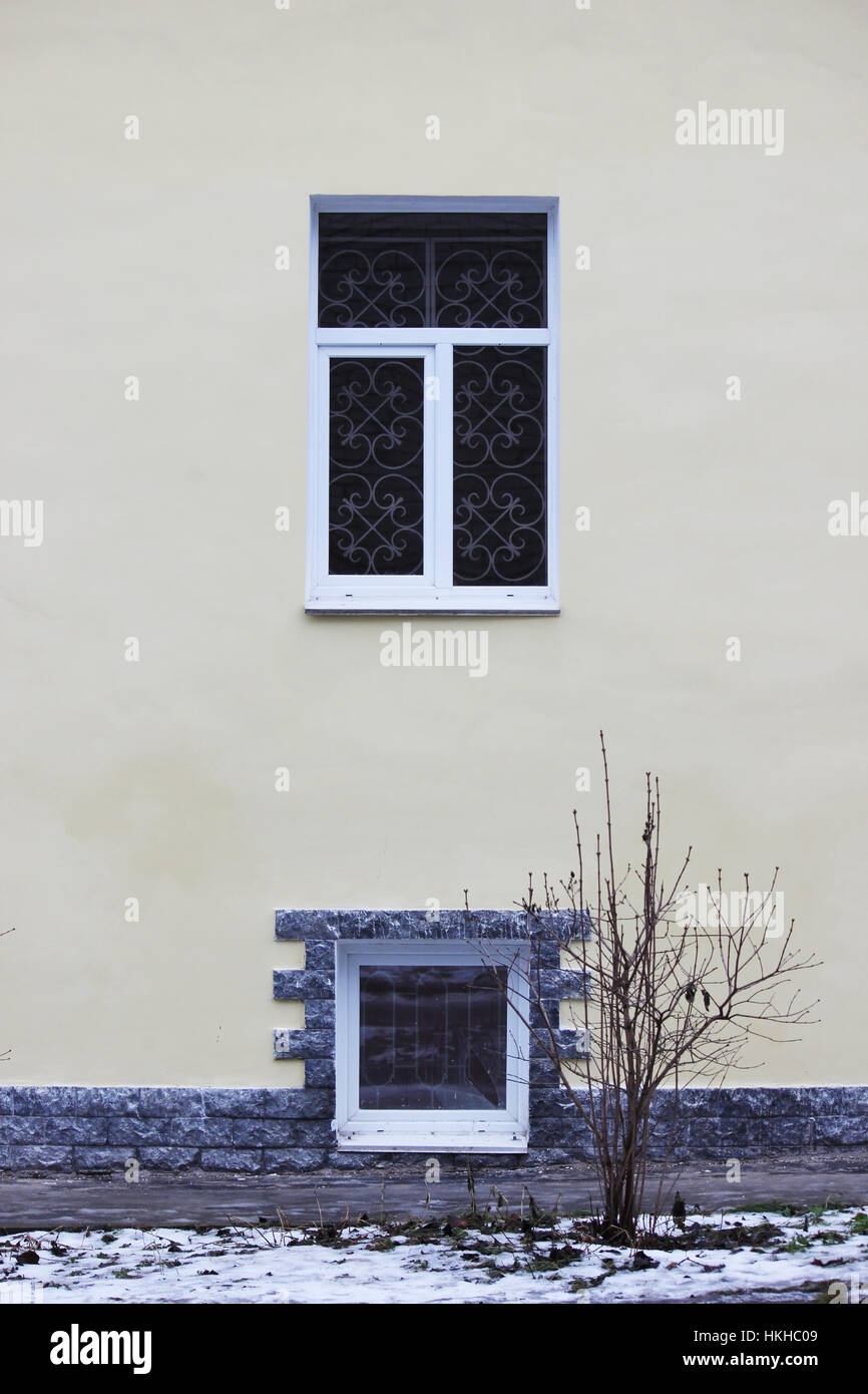 Beige Außenwand des Hauses, zwei Fenster und Transformator-Gehäuse Stockfoto