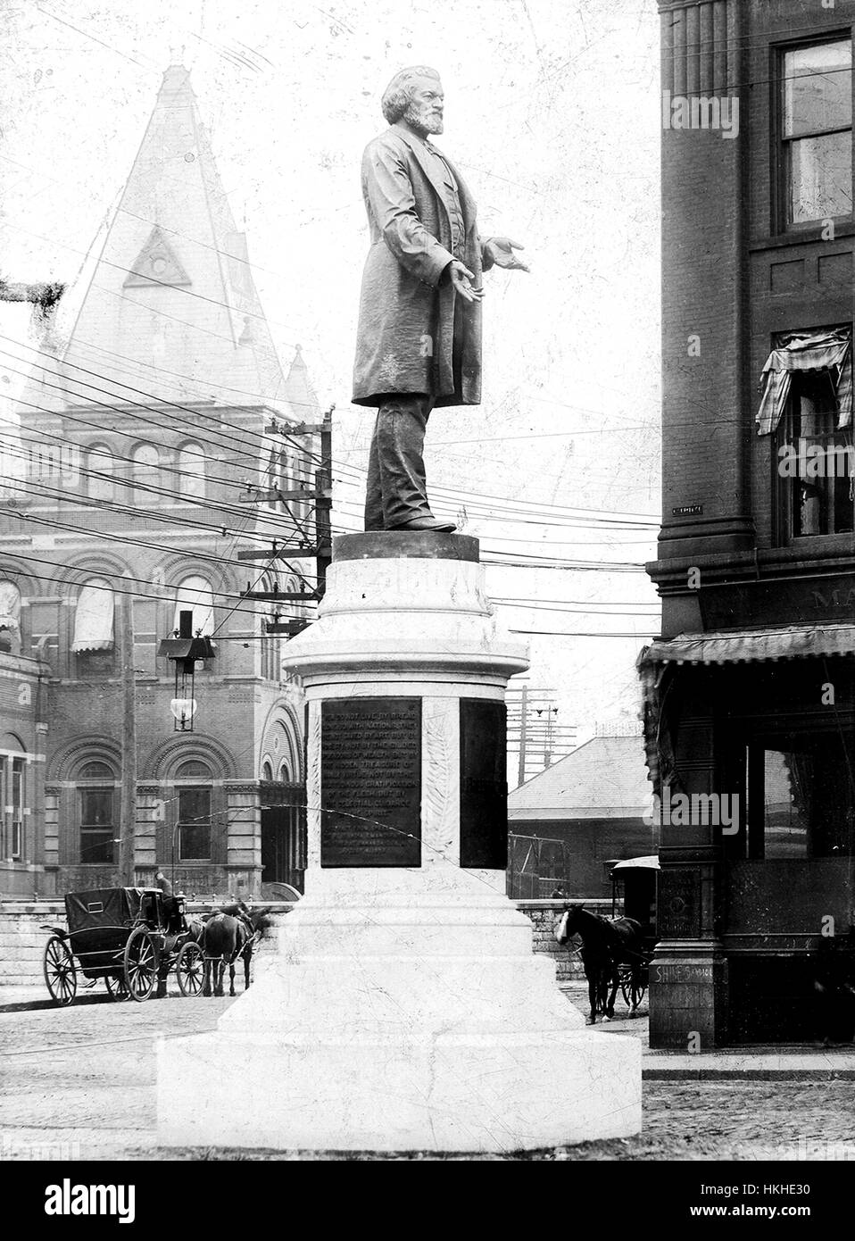 Ein Denkmal um zu Ehren von Frederick Douglass, eine Statue von Douglass steht auf einem Steinsockel, die mehrere Plaketten Text, Mauerwerk Gebäude, Straßen, enthält und Pferdekutschen sehen im Hintergrund, Douglass wurde einem entflohenen Sklaven, ein prominenter Abolitionisten wurde, er war bekannt für seine rednerischen Fähigkeiten und seine Unterstützung der gleichen Rechte für alle Menschen unabhängig von Rasse , Nationalität oder Geschlecht, diese Statue war das erste in den Vereinigten Staaten, eine Afrika-amerikanischer Staatsbürger, Rochester, New York, 1900 zu Ehren. Von der New York Public Library. Stockfoto