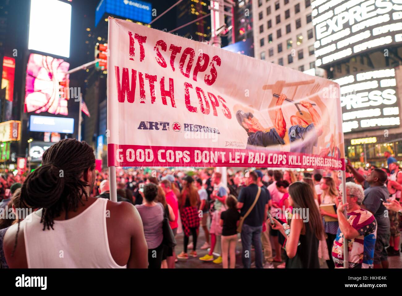 Während einer Black lebt Angelegenheit Protestaktion in New York Citys halten Times Square nach den Dreharbeiten Tod von Alton Sterling und Philando Kastilien, einer jungen afroamerikanischen Aktivistin und eine ausgereifte kaukasischen Aktivist ein Schild mit der Aufschrift "Es Haltestellen mit Cops", 7. Juli 2016. Stockfoto