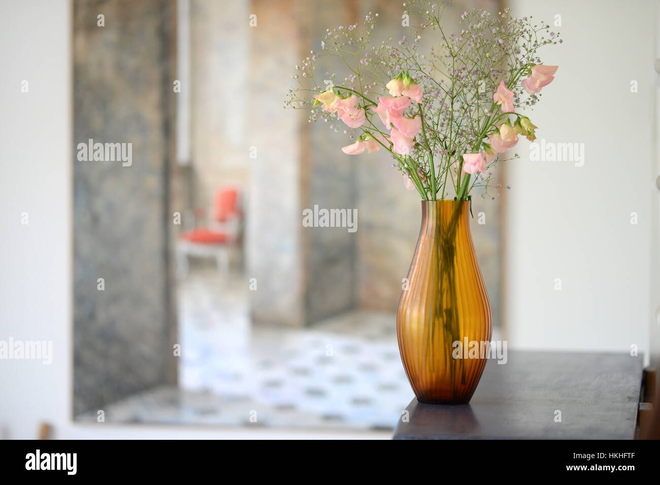 Braunglas geriffelte Vase mit Blumen in einem Raum Stockfoto