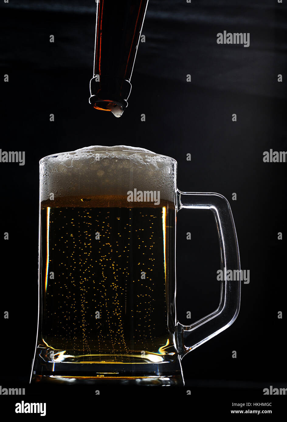 Volle Bierglas mit Schaum und Flasche mit Tropfen Stockfoto