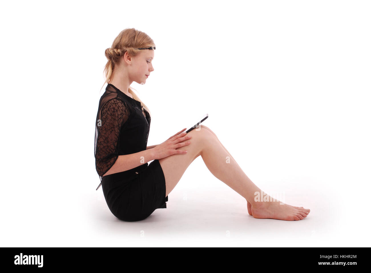 Mädchen sucht im Tablet pc sitzen isoliert auf weiss Stockfoto