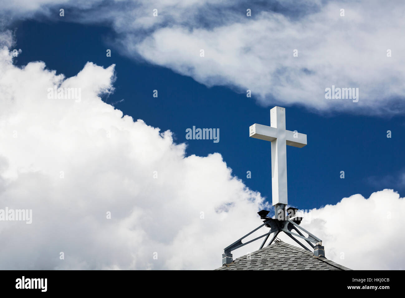 Weisses Kreuz auf einem Gipfel Dach mit tiefblauen Himmel und weiße Wolken; Calgary, Alberta, Kanada Stockfoto