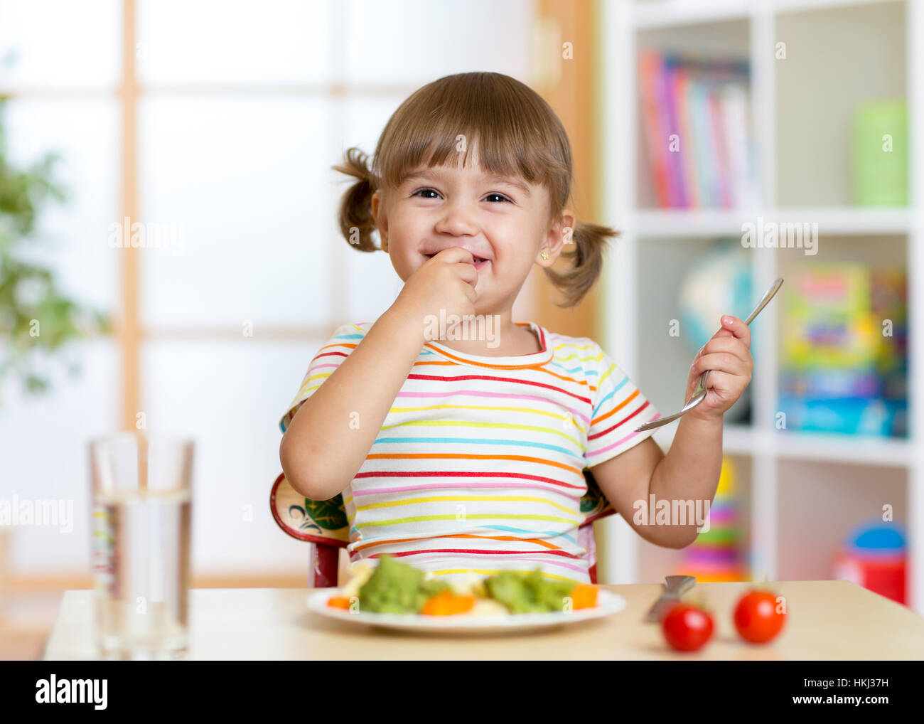 Lustige kleine Mädchen, die gesunde Ernährung im kindergarten Stockfoto