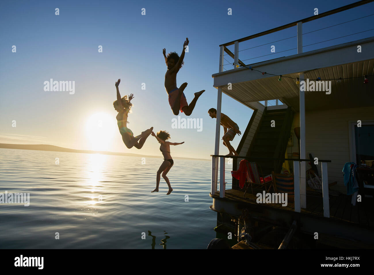 Junge Erwachsene Freunde abspringen Sommer Hausboot in Sonnenuntergang Ozean Stockfoto