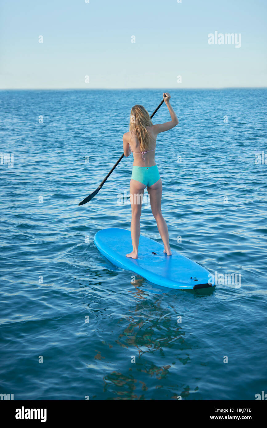 Junge Frau im Bikini Paddling im Sommer Ozean Stockfoto