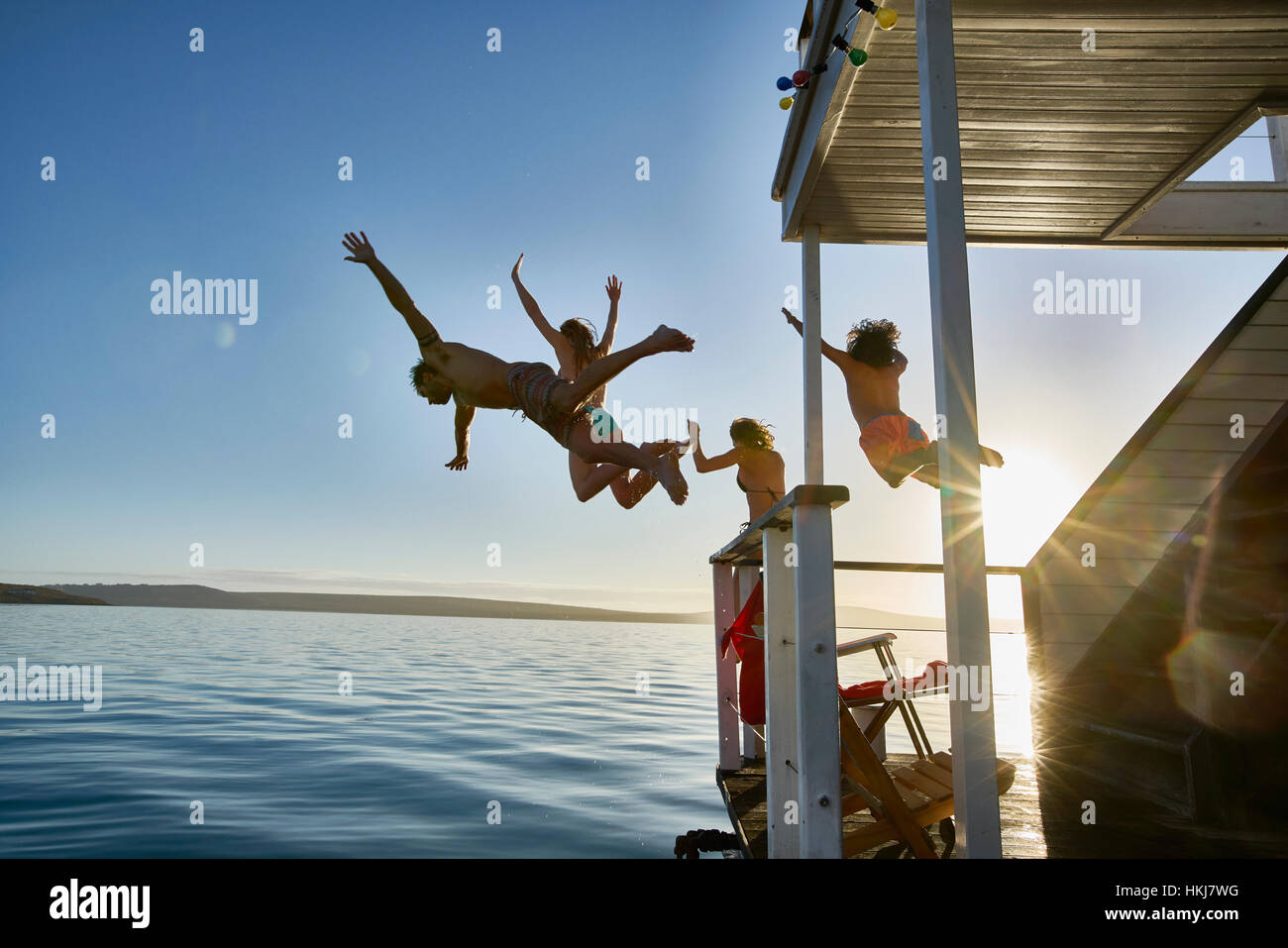 Junge Erwachsene Freunde von Sommer Hausboot in sonnigen Meer springen Stockfoto