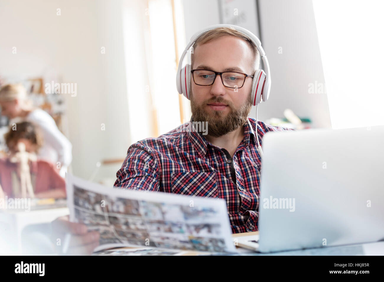 Design-Profi anhören von Musik mit Kopfhörern, die Überprüfung der Nachweise auf laptop Stockfoto