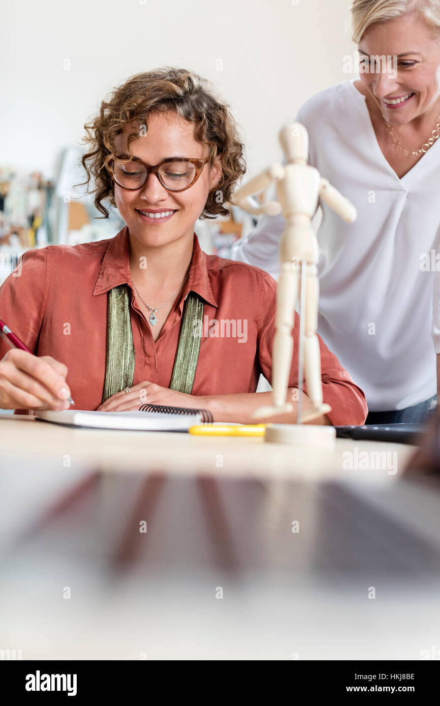 Weibliche Design-Profis mit des Künstlers Figur skizzieren im Büro Stockfoto