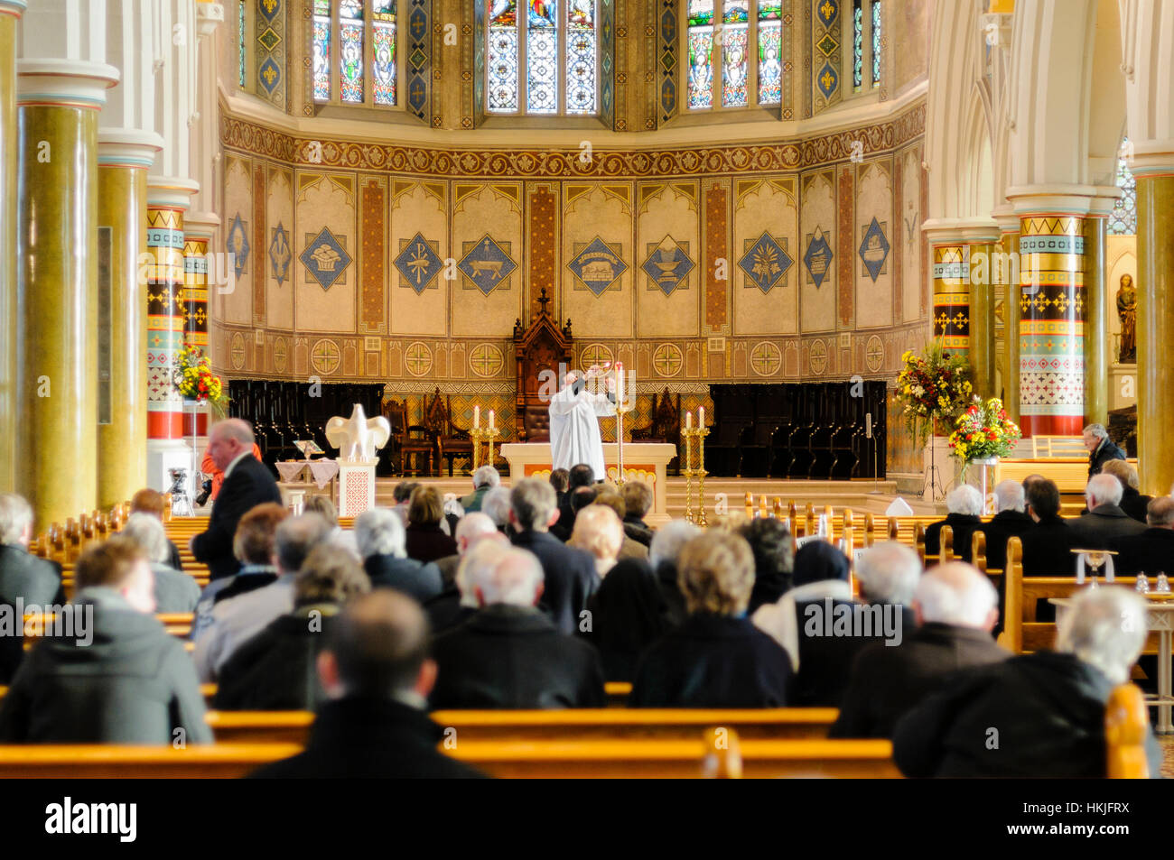Ein Priester zündet eine Kerze in einer katholischen Kapelle während einer Messe. Stockfoto