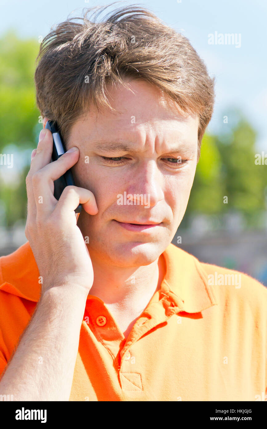 Ernster Mann sprechen von Mobilfunk in der Farbe orange Stockfoto
