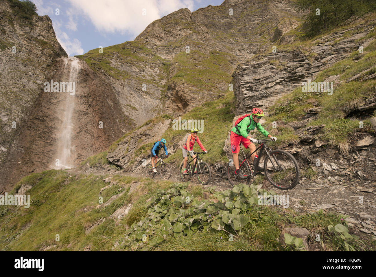 Drei Mountainbiker fahren auf Hügel am Wasserfall, Zillertal, Tirol, Österreich Stockfoto