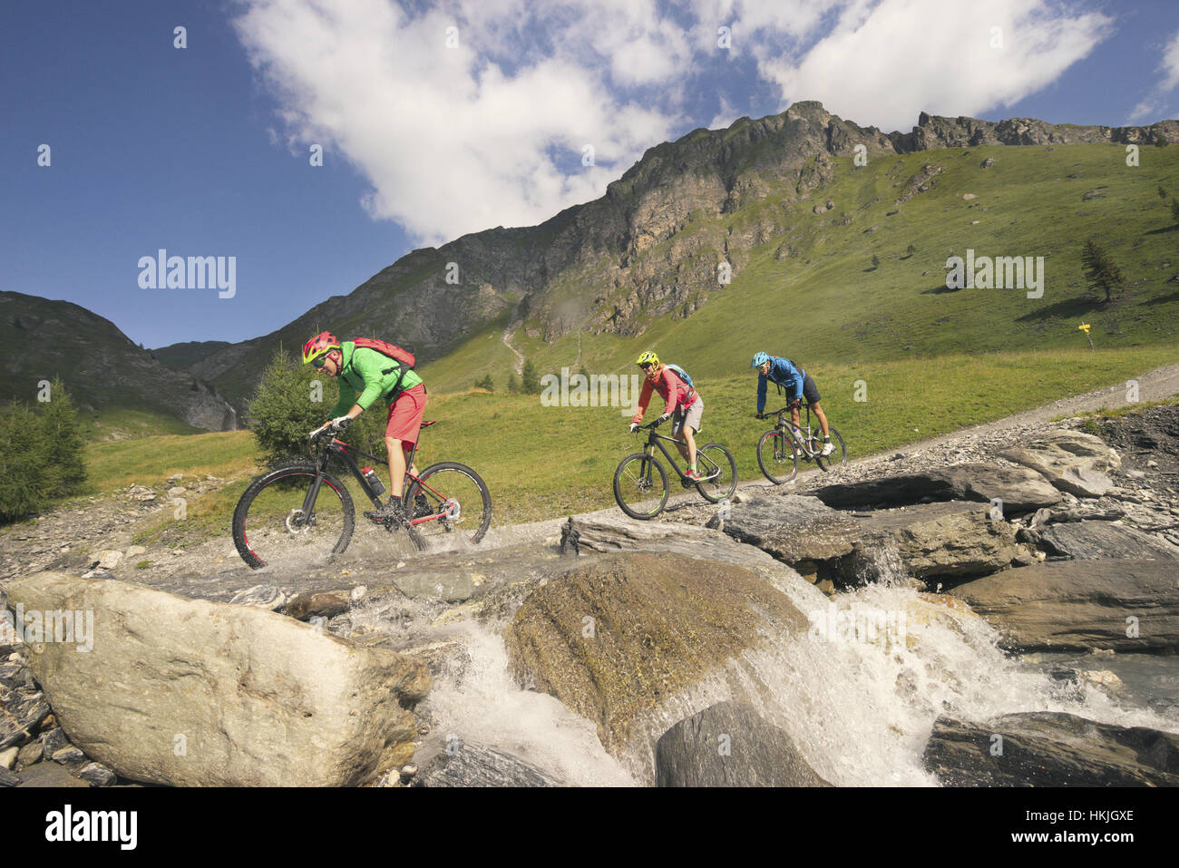 Drei Mountainbiker über Bach am Berg, Zillertal, Tirol, Österreich Stockfoto