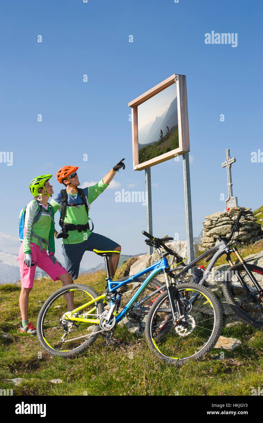 Junges Paar Mountainbiker gerade Infotafel weiter bergan, Zillertal, Tirol, Österreich Stockfoto