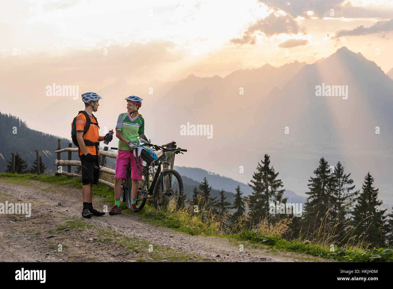 Junges Paar Mountainbiker stehen auf Feldweg während Sonnenuntergang, Zillertal, Tirol, Österreich Stockfoto
