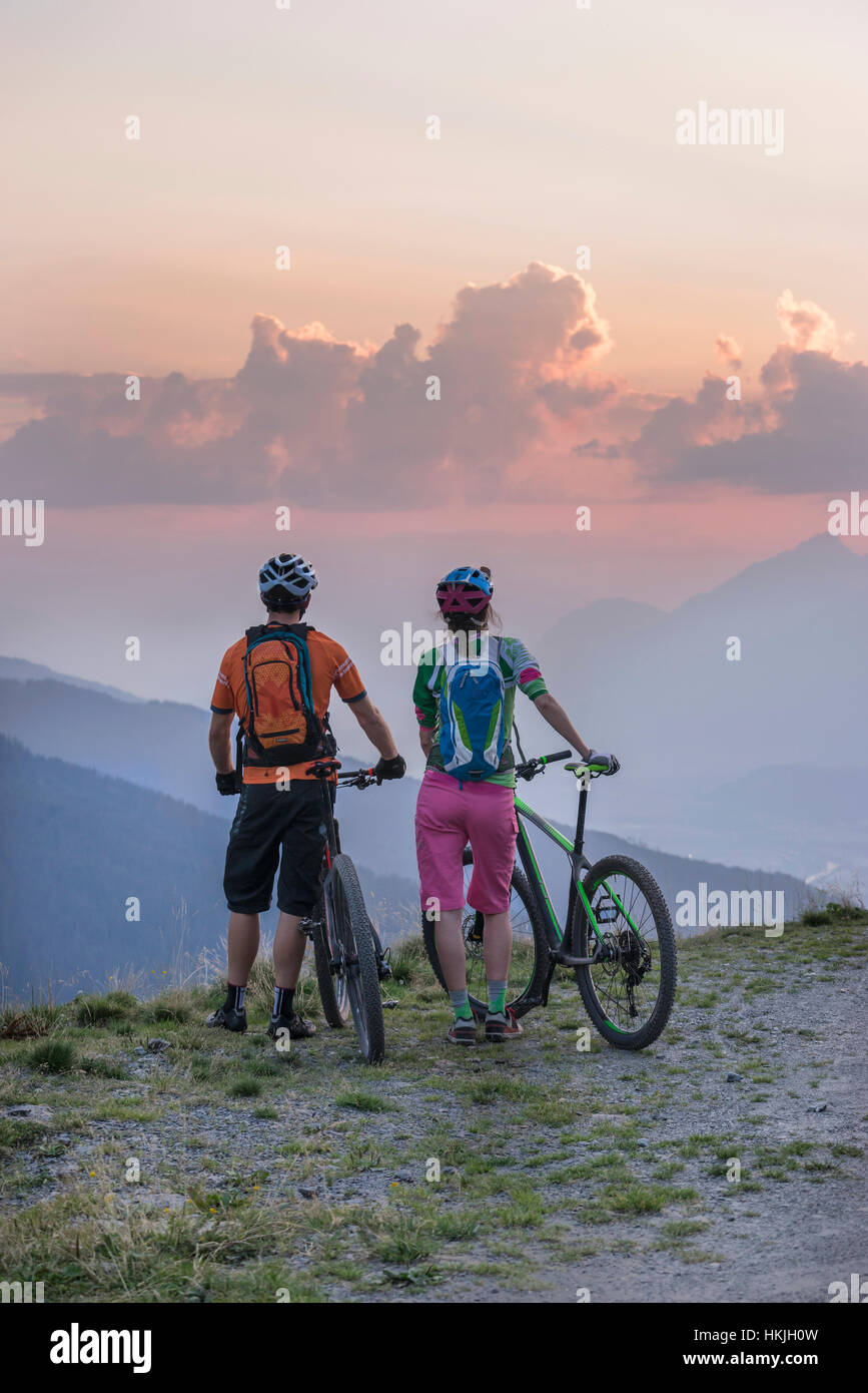 Rückansicht des jungen Paares der Mountainbiker in die alpine Landschaft stehen und betrachten während Sonnenuntergang, Zillertal, Tirol, Österreich Stockfoto
