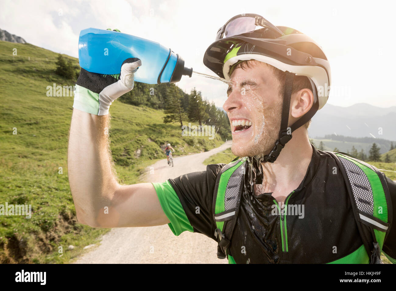 Mountainbiker gießt Wasser auf seinem Gesicht, Kampenwand, Bayern, Deutschland Stockfoto