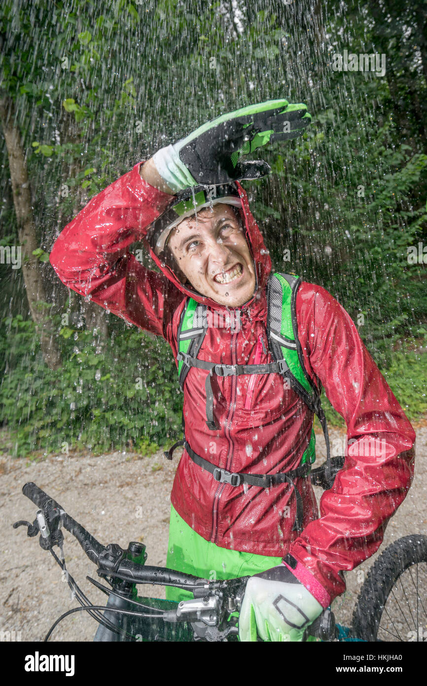 Mountainbiker stehen im Regen mit der Hand über den Kopf, Kampenwand, Bayern, Deutschland Stockfoto