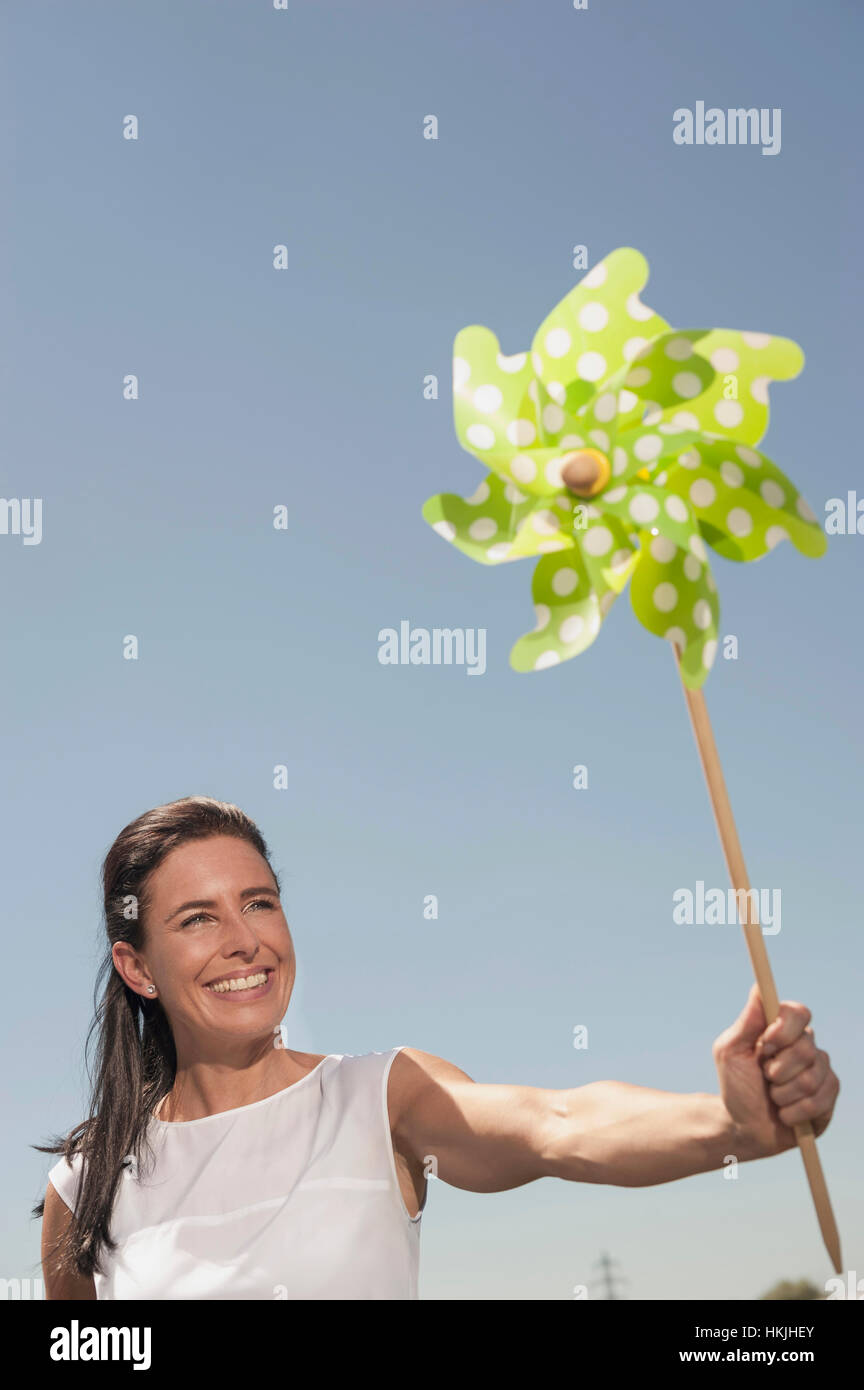 Glückliche Frau mit Papier Windmühle am geothermischen Kraftwerk, Bayern, Deutschland Stockfoto