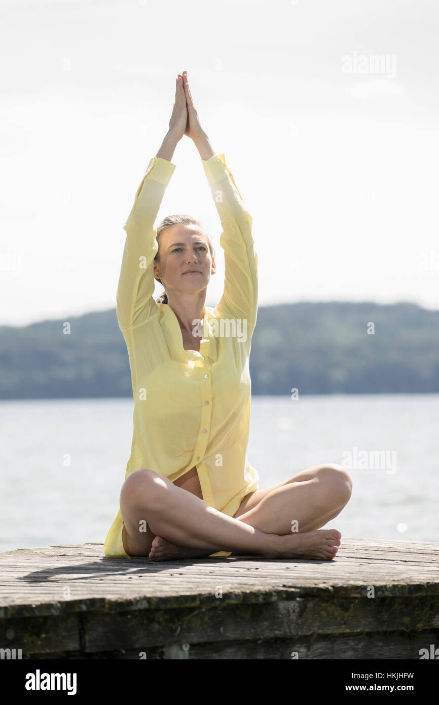 Frau beim Lotus Pose Yoga auf Steg am See, Ammersee, Oberbayern, Deutschland Stockfoto