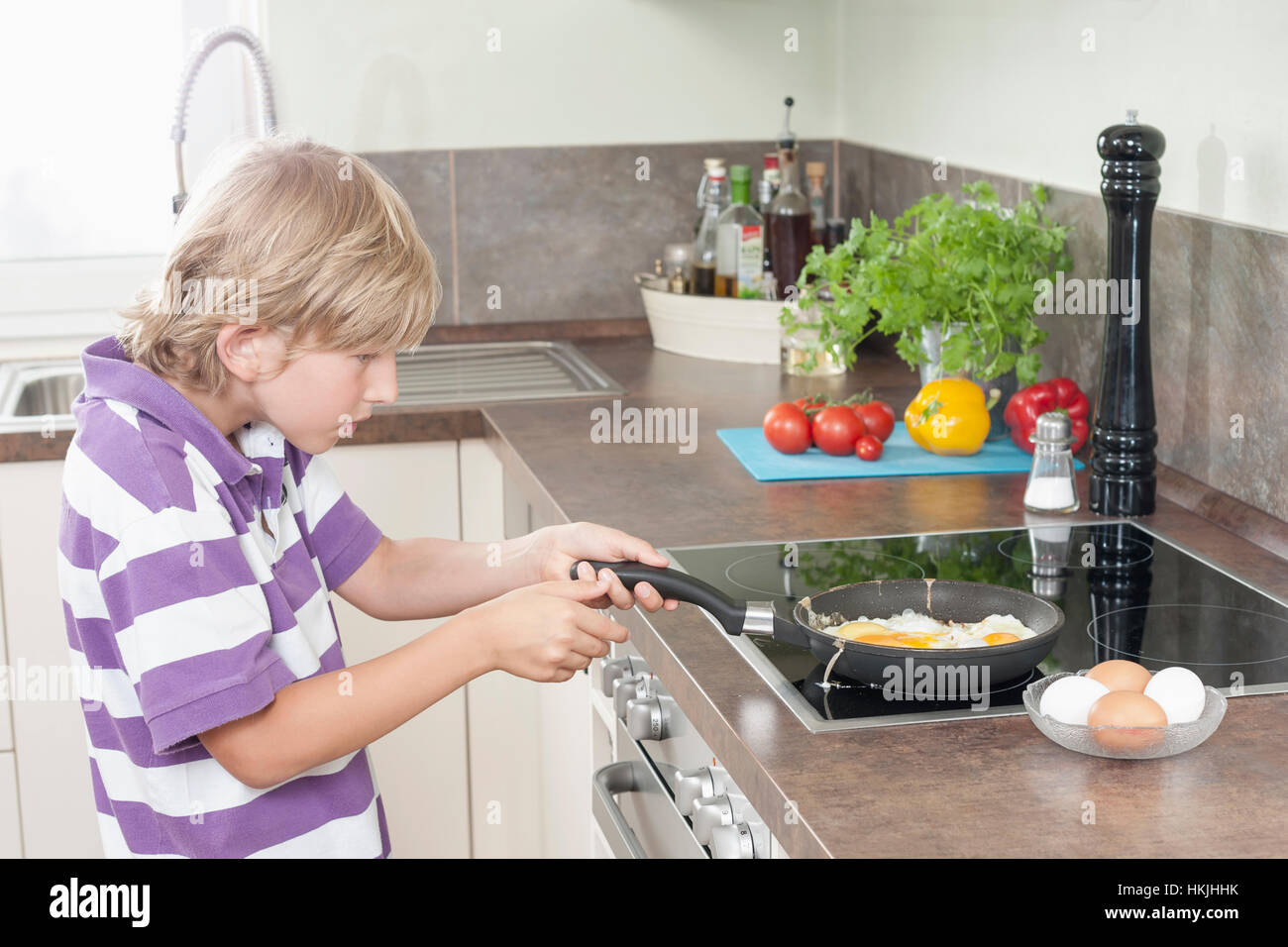 Junge Vorbereitung Spiegeleier in Küche, Bayern, Deutschland Stockfoto