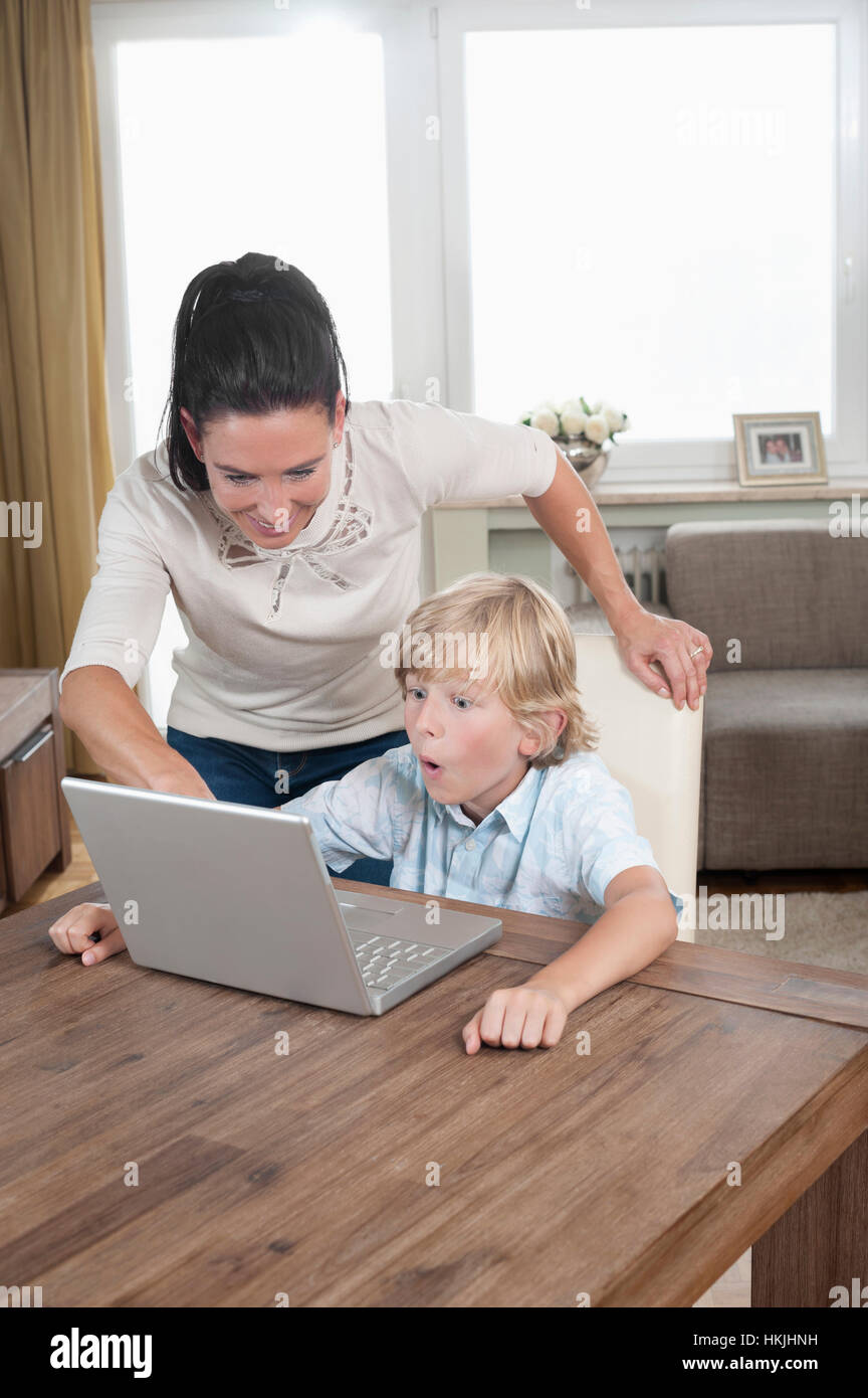 Frau mit ihrem Sohn mit Laptop im Wohnzimmer, Bayern, Deutschland Stockfoto