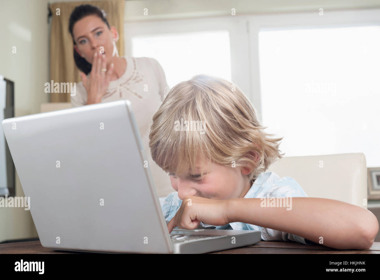 Schockiert Frau, die gerade ihren Sohn mit Laptop im Wohnzimmer, Bayern, Deutschland Stockfoto