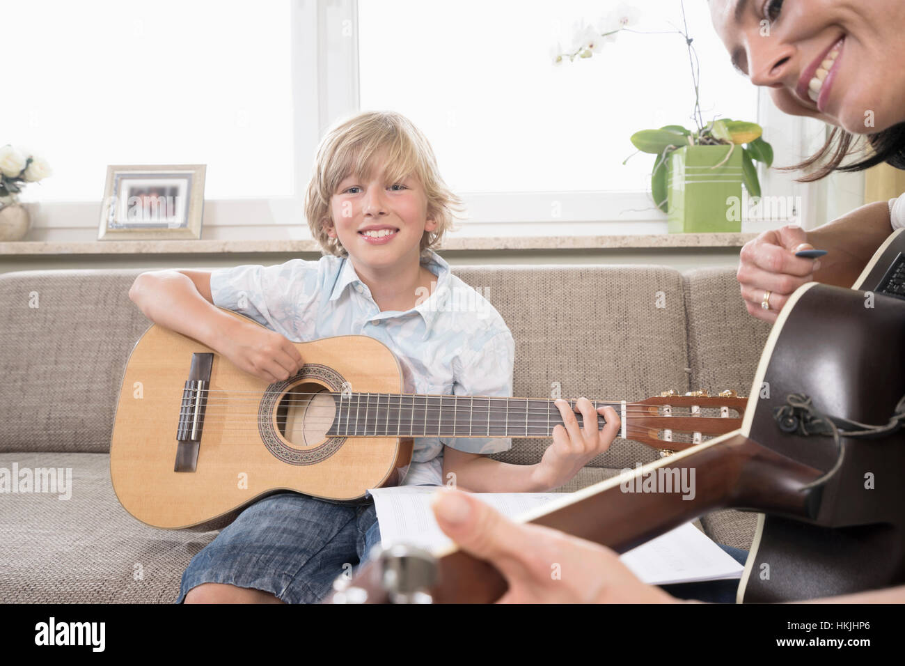 Frau mit ihrem Sohn Gitarrespielen in Wohnzimmer, Bayern, Deutschland Stockfoto