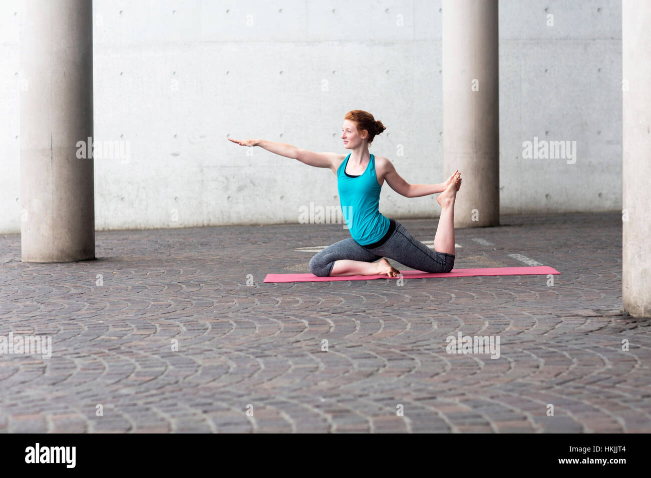 Junge Frau beim Yoga auf Gymnastikmatte in Großstadt, Freiburg Im Breisgau, Baden-Württemberg, Deutschland Stockfoto