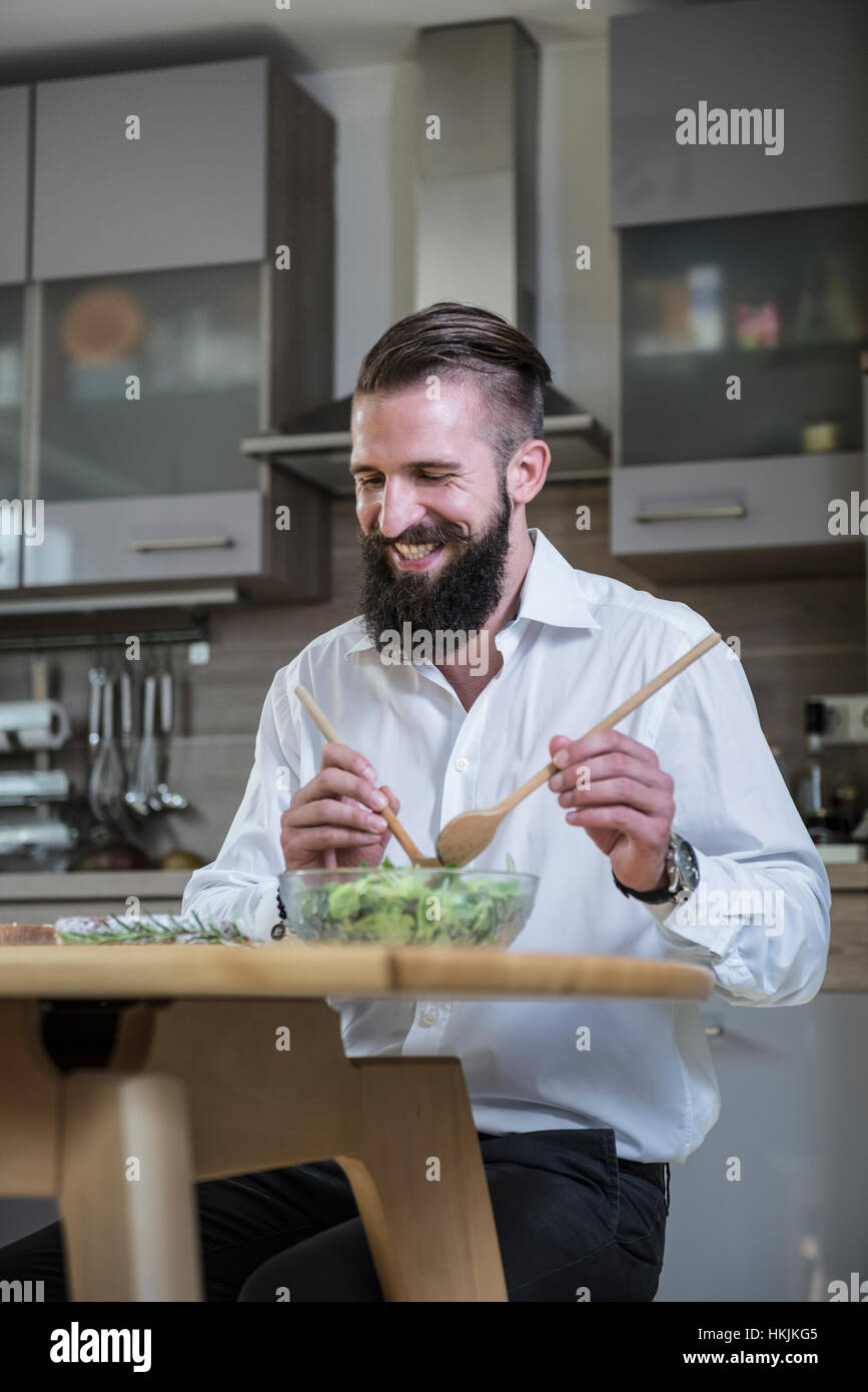 Mann bereitet Salat in der Küche und lächelnd, Bayern, Deutschland Stockfoto