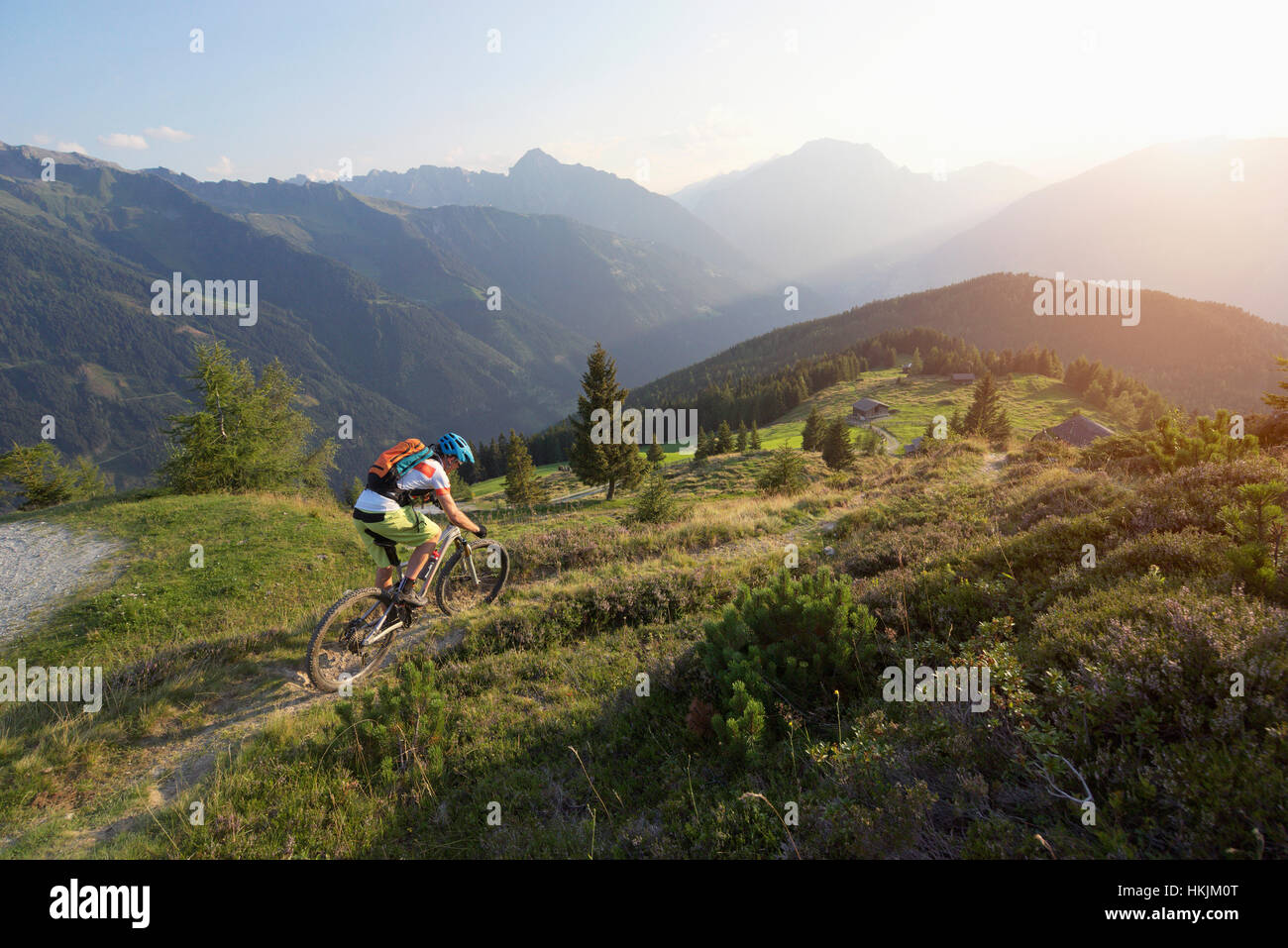 Mountainbiker fahren weiter bergan in alpiner Landschaft bei Sonnenuntergang, Zillertal, Tirol, Österreich Stockfoto