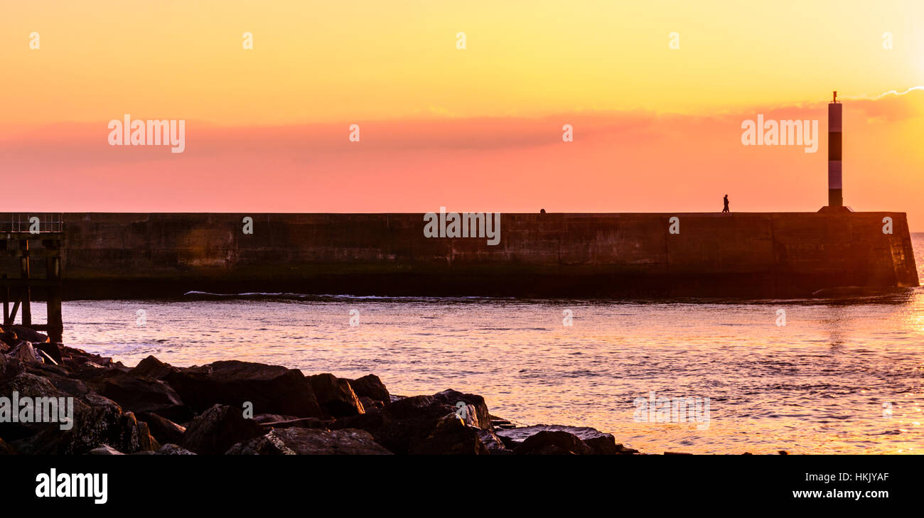 Ein junger Mann, Blick auf das Meer bei Sonnenuntergang in Aberystwyth, Wales Stockfoto