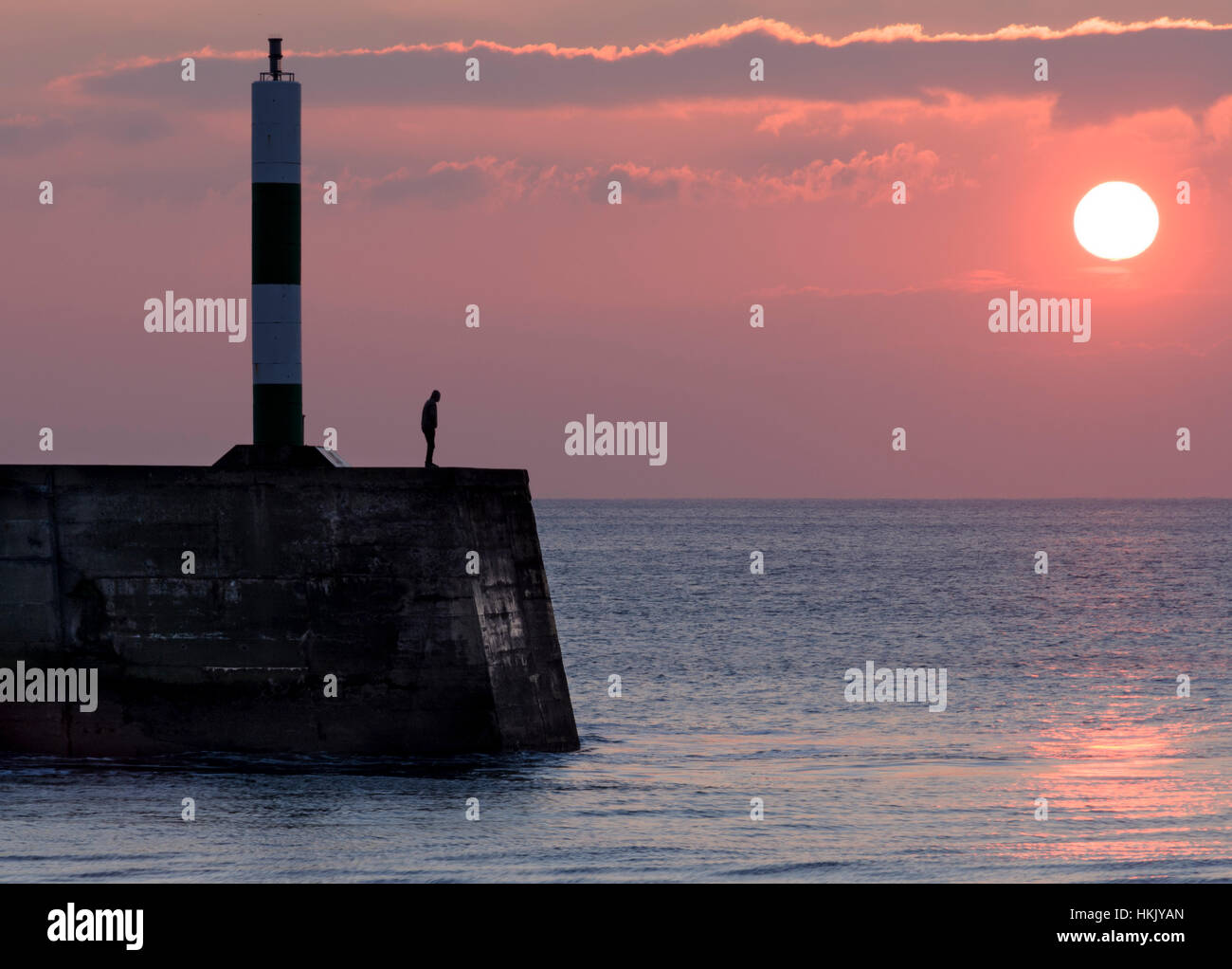 Ein junger Mann, Blick auf das Meer bei Sonnenuntergang in Aberystwyth, Wales Stockfoto