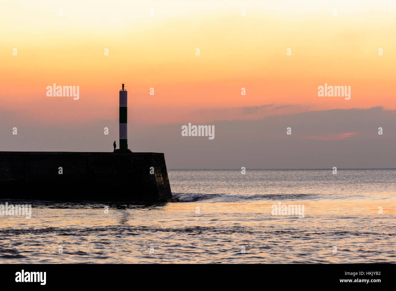 Ein junger Mann, Blick auf das Meer bei Sonnenuntergang in Aberystwyth, Wales Stockfoto