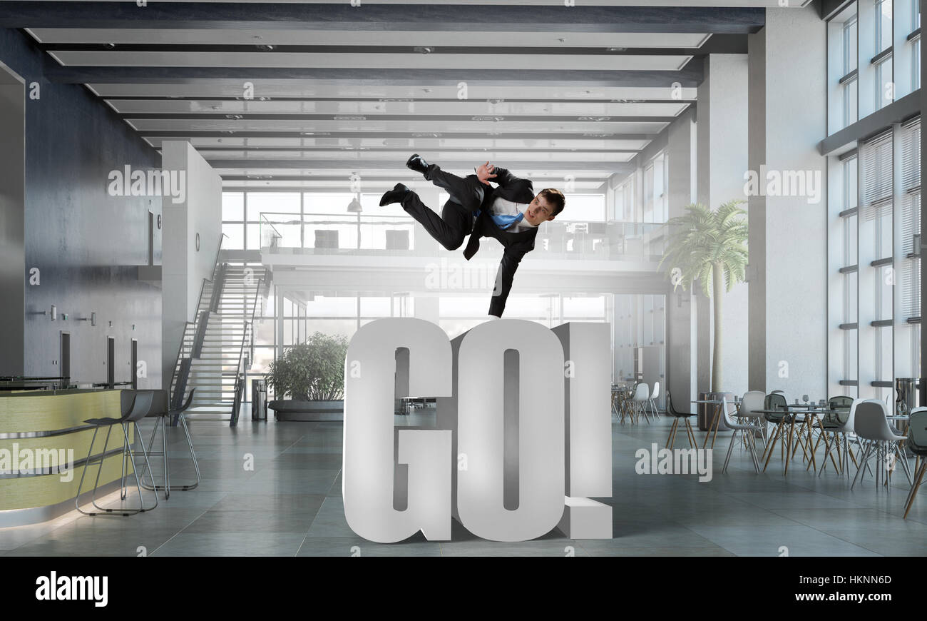 Fröhliche Jungunternehmer tanzen in seinem Büro. Mixed-media Stockfoto