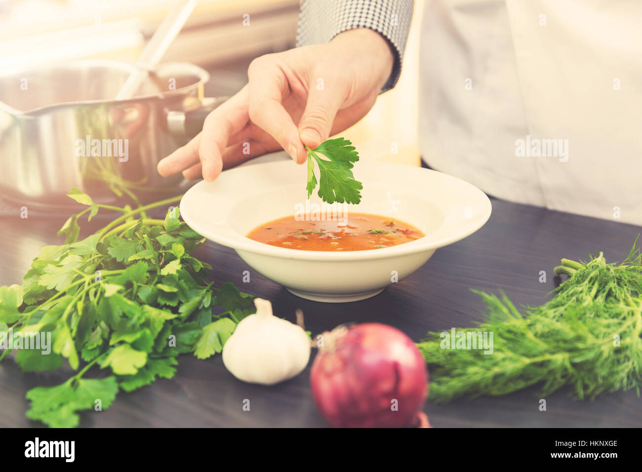 Koch, Dekoration Suppe mit Kräutern in der Küche Stockfoto