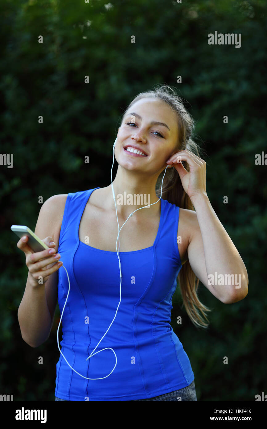 Happy Fitness-Frau mit Kopfhörern hält eine Telefon vor dem training Stockfoto