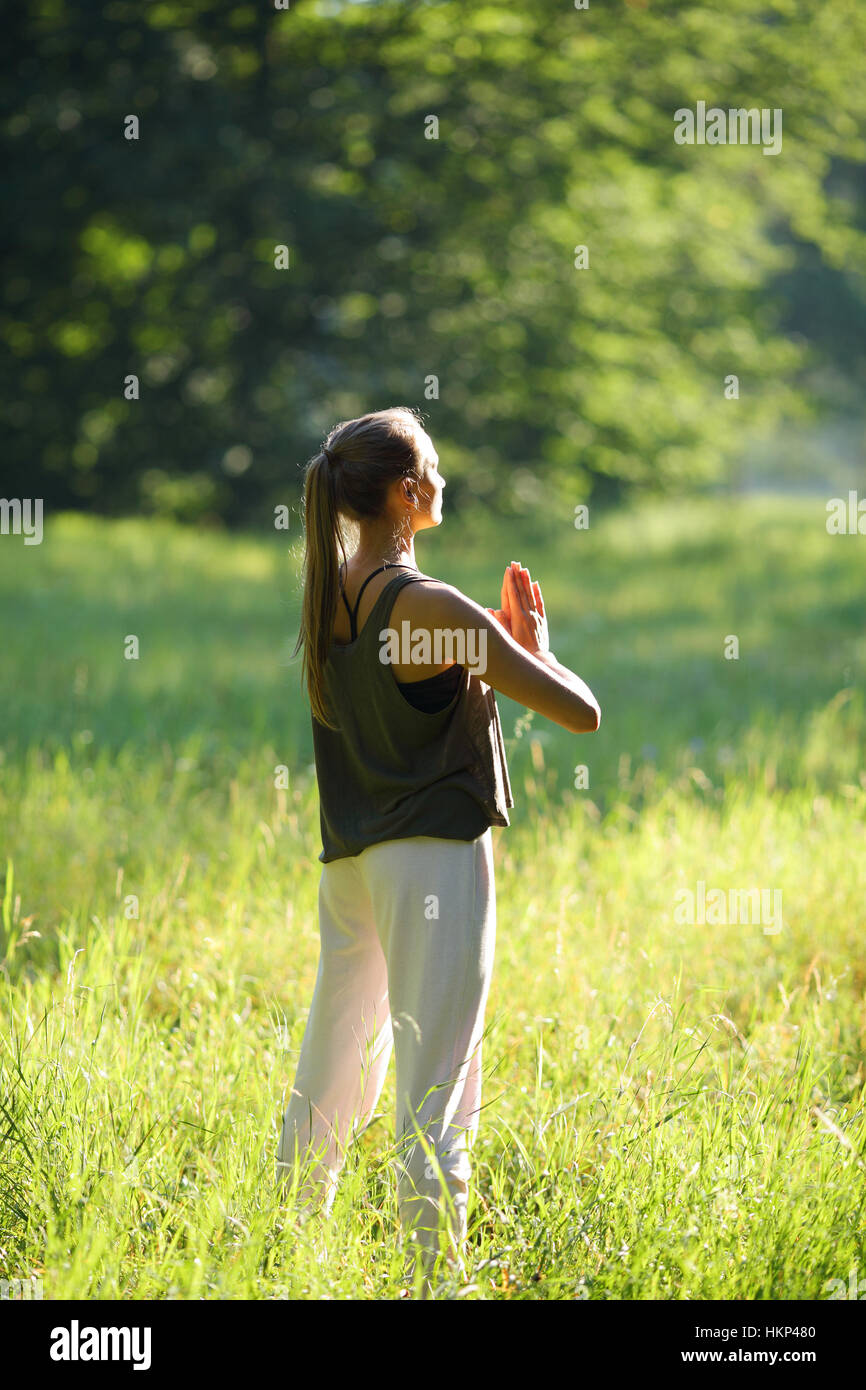 Junge Frau meditiert im Wald mit Praing Händen stehen Stockfoto