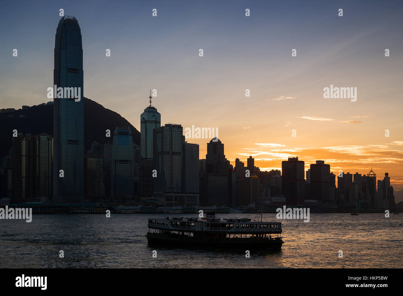 Silhouette von einem Star Ferry und Wolkenkratzern auf Hong Kong Island in Hongkong bei Sonnenuntergang. Von Tsim Sha Tsui, Kowloon betrachtet. Stockfoto