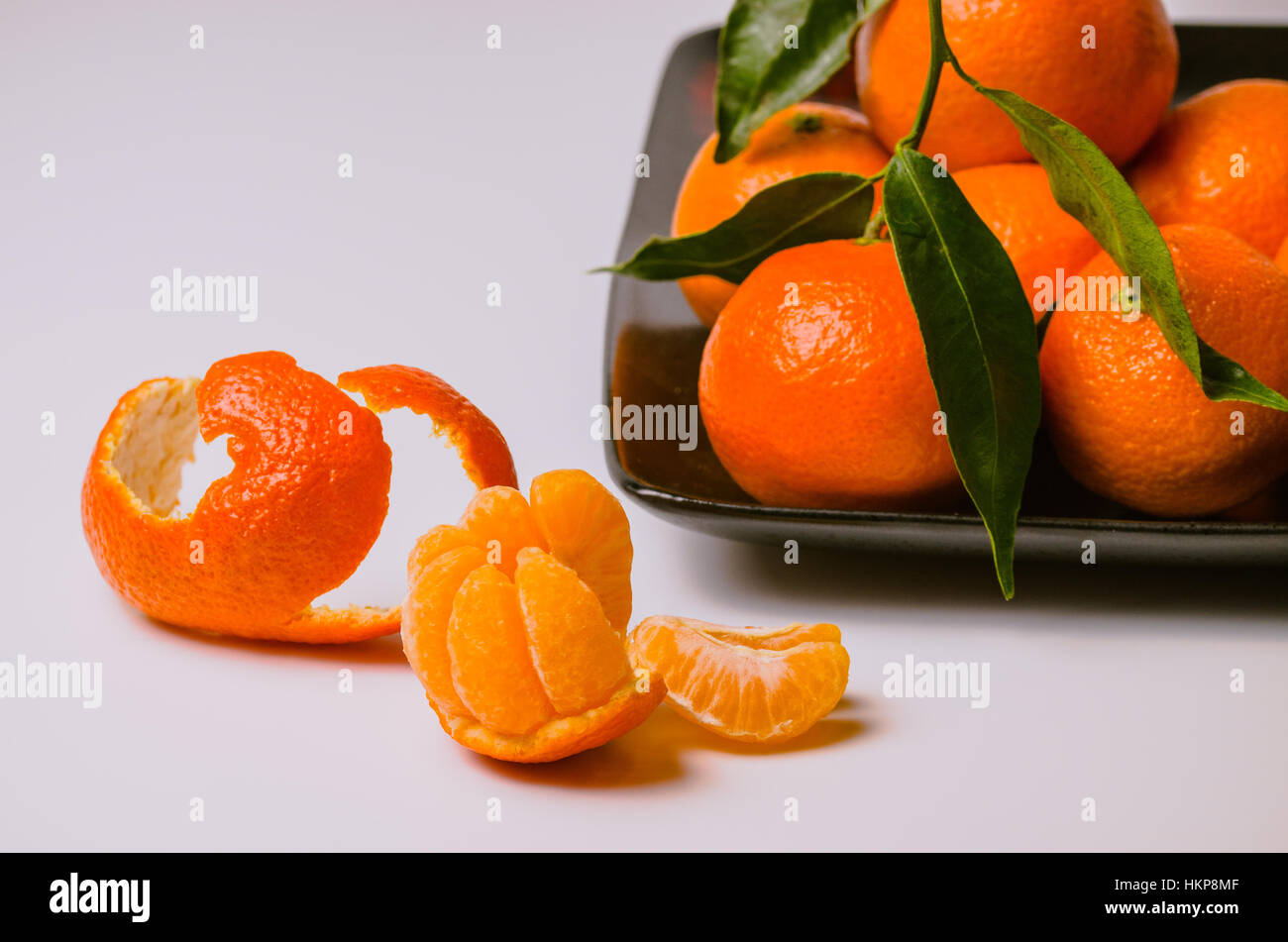 Mehreren Clementine tropische Früchte, ganze und geschälte auf weißem Hintergrund mit Platz für Text. Stockfoto