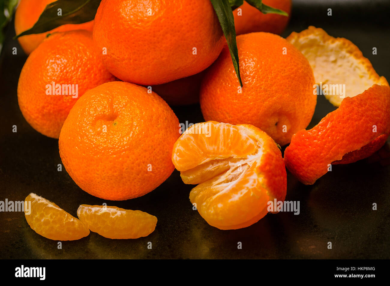 Mehrere frische saftige Clementine tropische Früchte auf schwarzen Druckplatte. Stockfoto