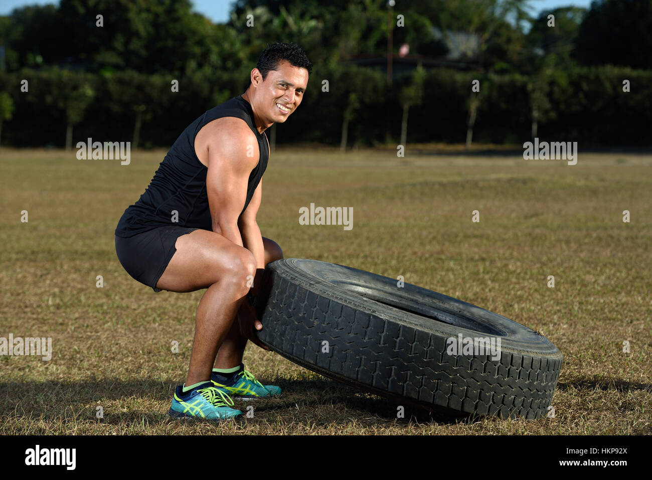 Sport lächelnder Mann spiegeln große Reifen am Stadion Stockfoto