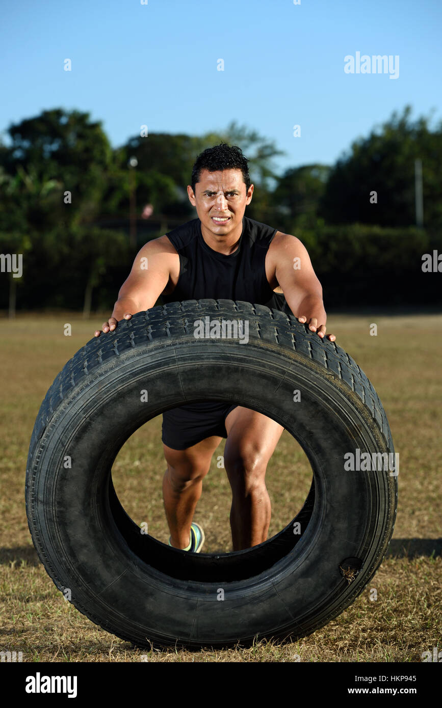 Mann-Athlet spiegeln große Reifen auf Stadion Rasen Stockfoto
