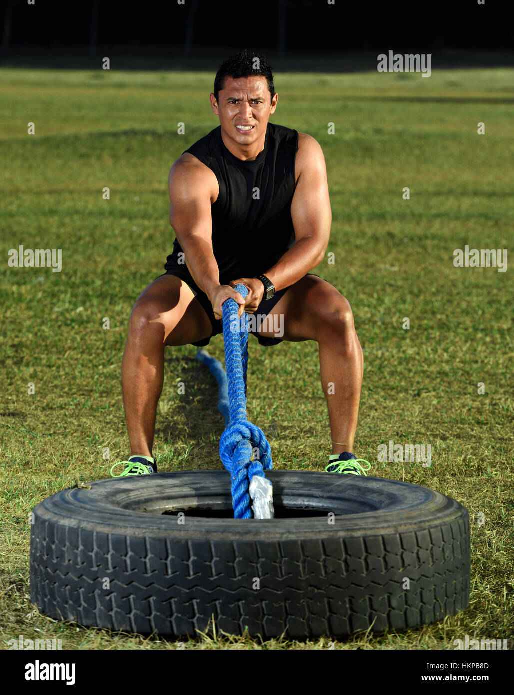 Sport Mann Pull Reifen auf dem grünen Rasen im park Stockfoto