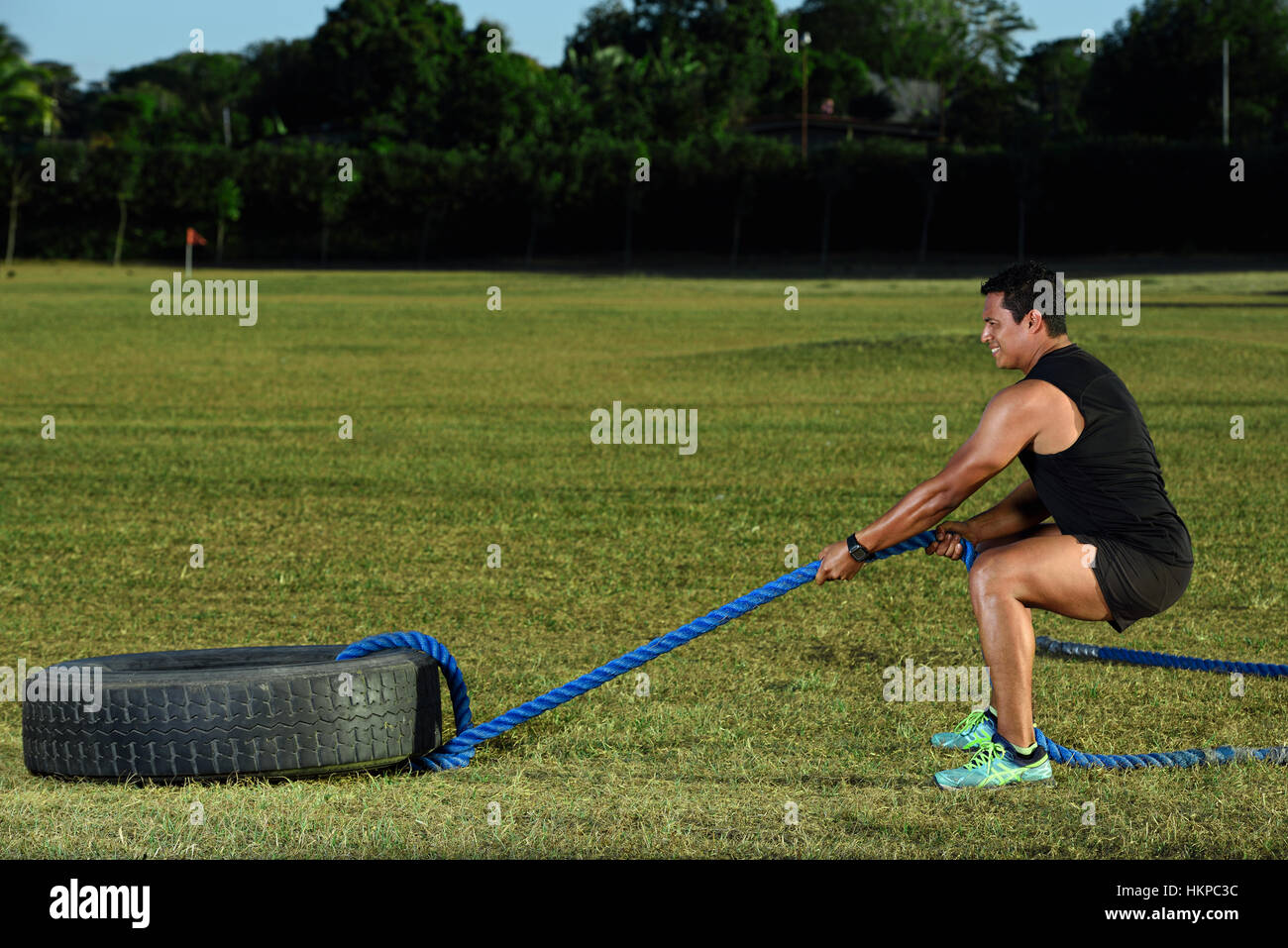 Sport Mann Push Reifen auf grünen Rasen park Stockfoto