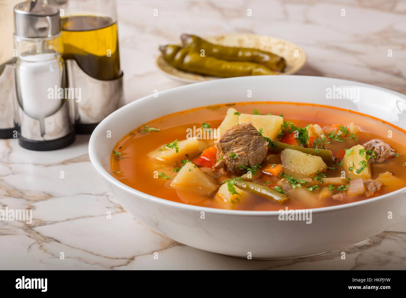 Schüssel mit Gemüse Rindfleisch Suppe und hot chili Peppers im Hintergrund Stockfoto