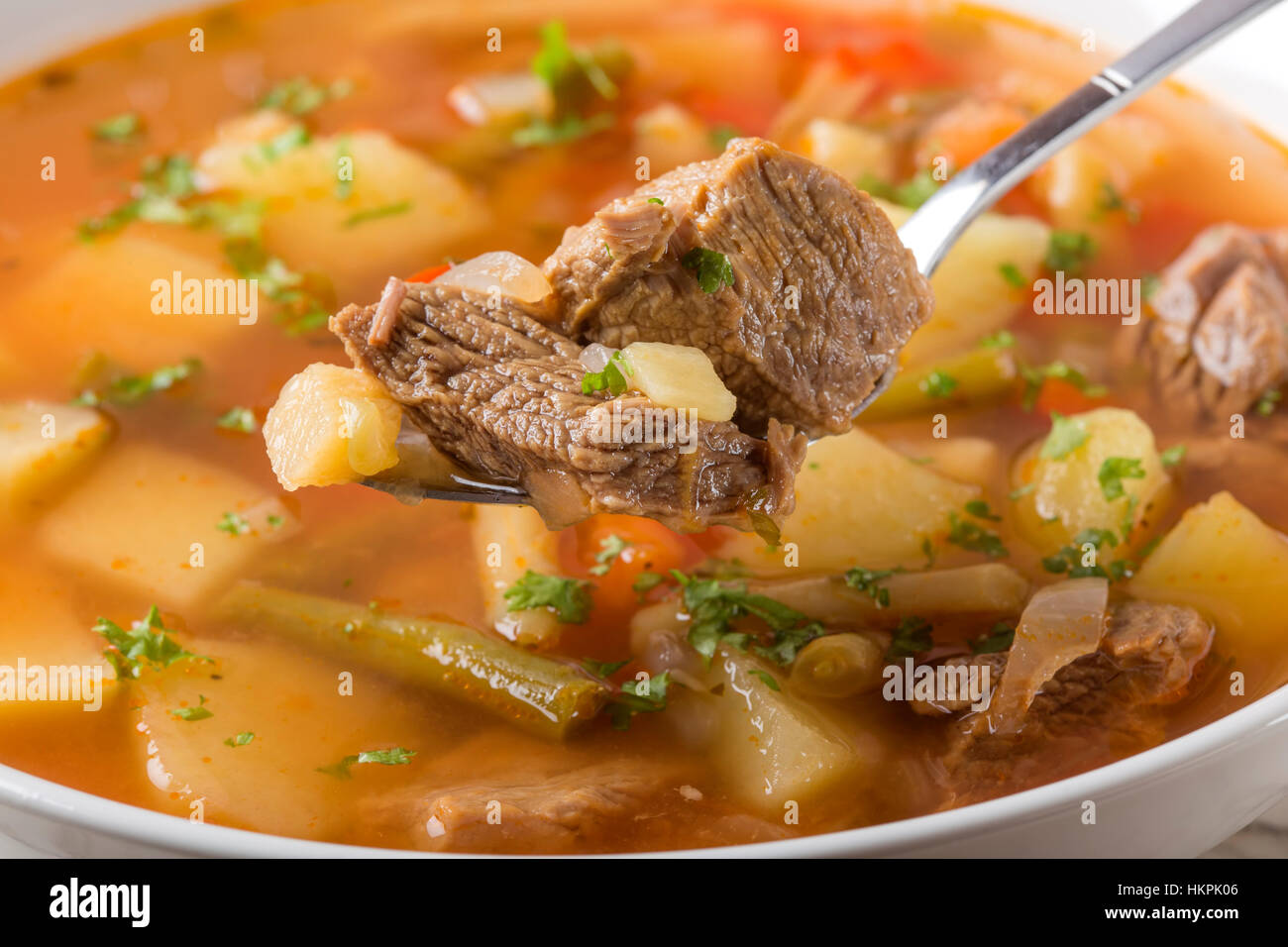 Nahaufnahme von Löffel gefüllt mit Gemüse Rindfleisch Suppe Stockfoto