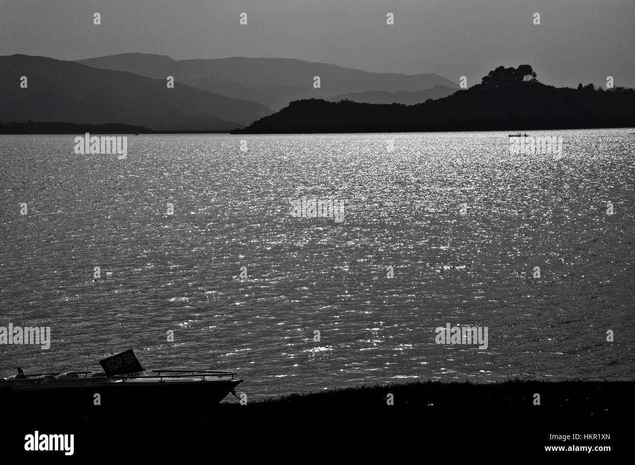 Boot am Ufer eines ruhigen Sees, umgeben von Bergen ruhen Stockfoto