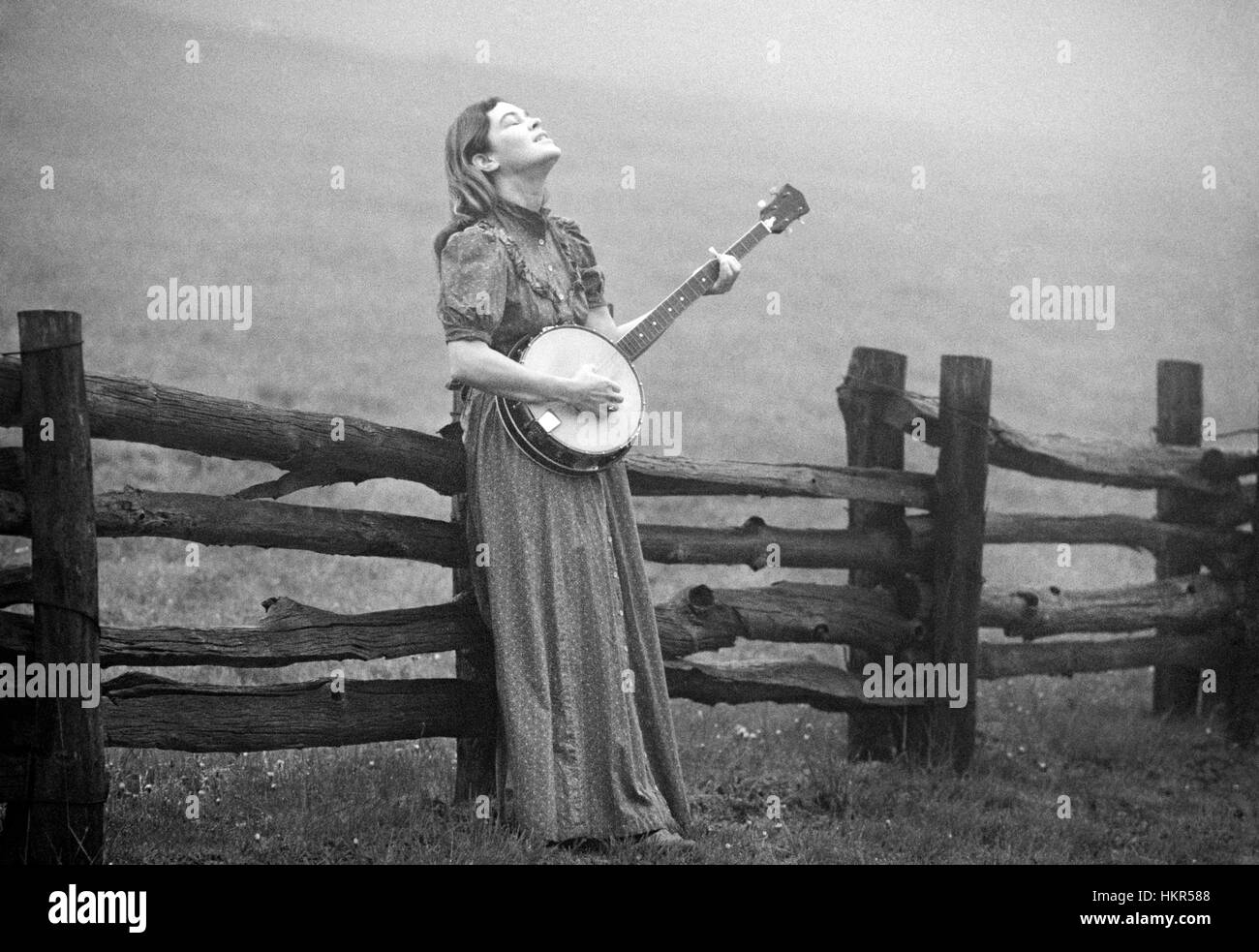 Eine junge Frau und ihre Banjo in einem nebligen Bauernhof Feld hoch in den Blue Ridge Mountains von North Carolina, am frühen Morgen im Sommer. Stockfoto